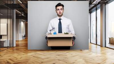 Getting fired. Handsome young businessman in suit in office with the box with his stuff Wall mural